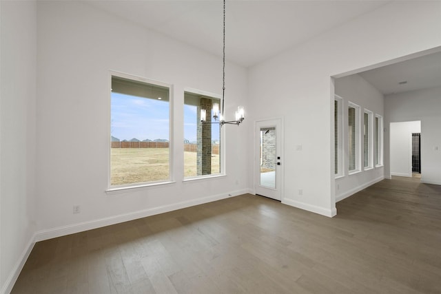 unfurnished dining area featuring a chandelier and dark hardwood / wood-style floors