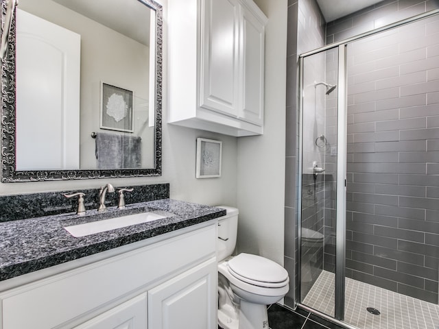 bathroom with tile patterned flooring, a shower with door, vanity, and toilet