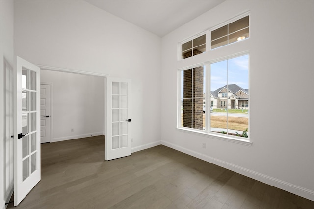 empty room with french doors, a high ceiling, and hardwood / wood-style flooring