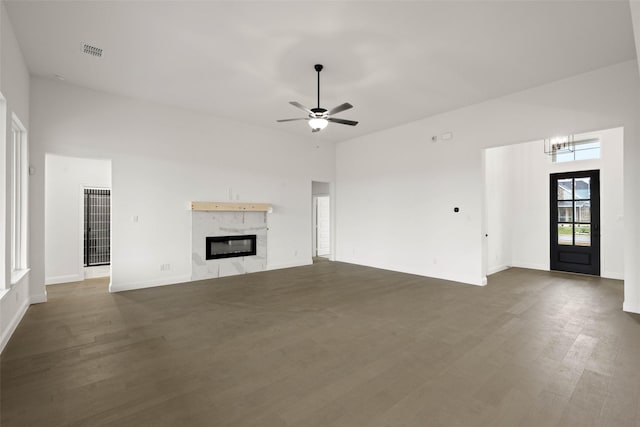 unfurnished living room with a fireplace, ceiling fan, and dark hardwood / wood-style flooring