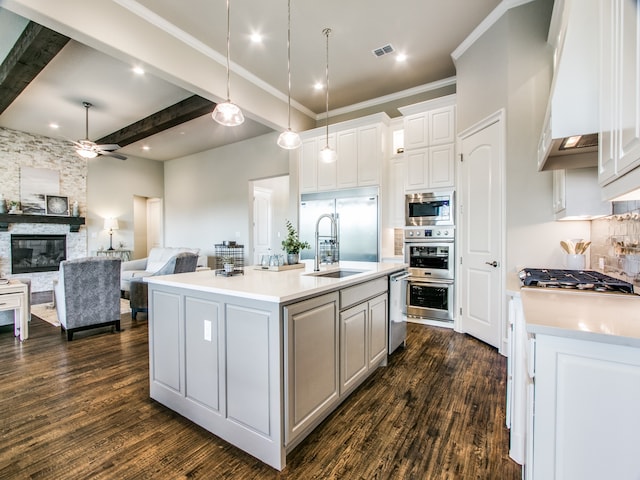 kitchen with an island with sink, beamed ceiling, white cabinets, dark hardwood / wood-style flooring, and a fireplace