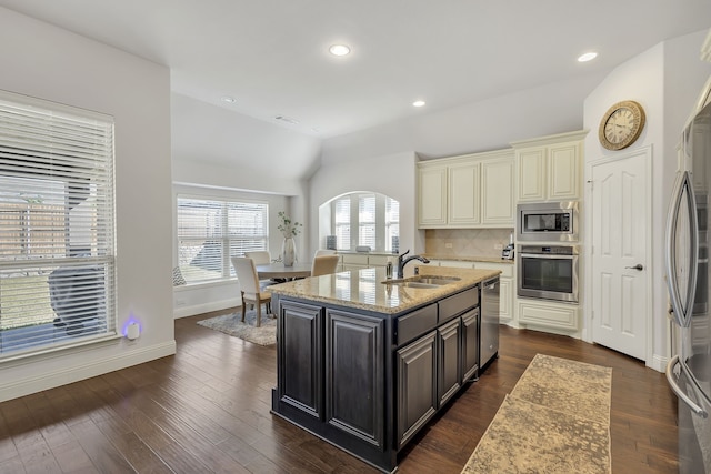 kitchen with lofted ceiling, sink, a center island with sink, dark wood-type flooring, and stainless steel appliances