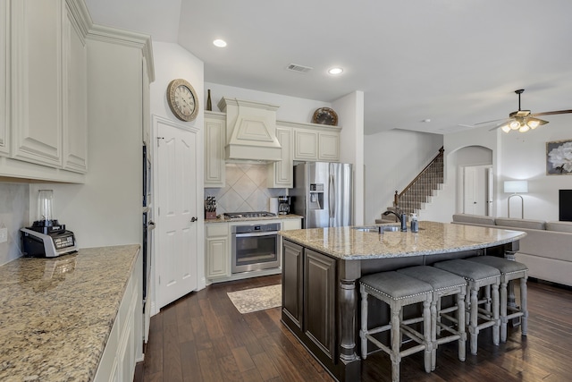 kitchen featuring appliances with stainless steel finishes, a breakfast bar, light stone countertops, dark hardwood / wood-style flooring, and custom exhaust hood