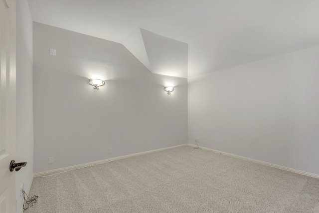 empty room with carpet floors and vaulted ceiling