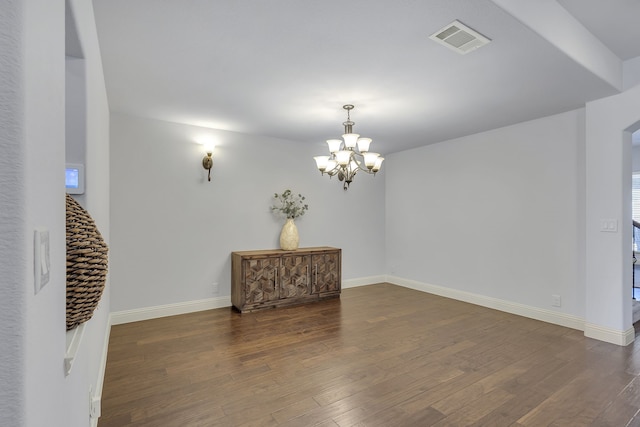 empty room featuring an inviting chandelier and dark wood-type flooring