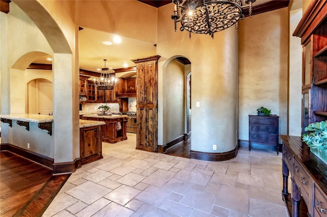 kitchen featuring light stone countertops, decorative light fixtures, a kitchen bar, double oven range, and a chandelier