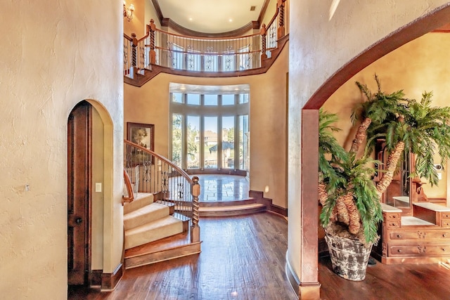 foyer with a high ceiling, wood-type flooring, and ornamental molding