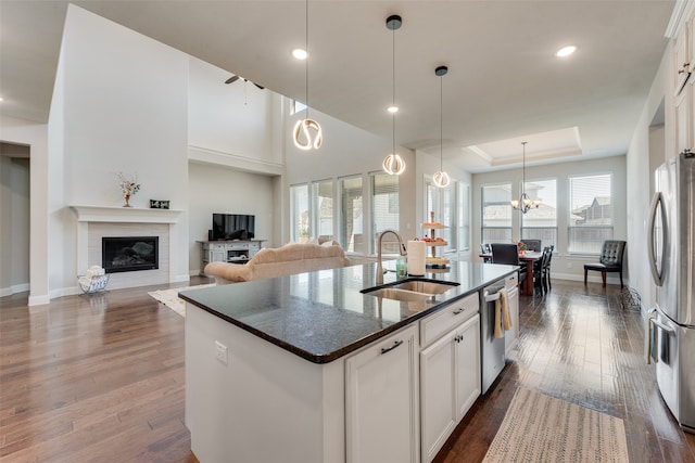 kitchen with an island with sink, white cabinets, pendant lighting, and sink