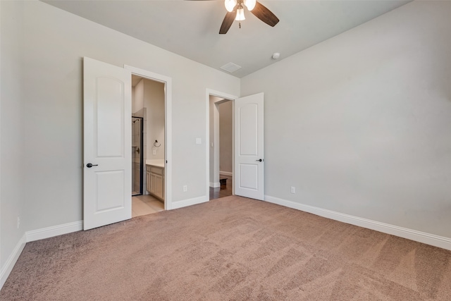 unfurnished bedroom featuring light carpet, ceiling fan, and ensuite bath