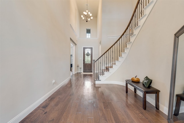 entryway with a notable chandelier, a towering ceiling, and dark hardwood / wood-style flooring