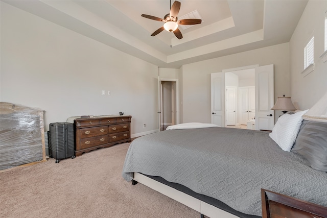 carpeted bedroom featuring a tray ceiling and ceiling fan