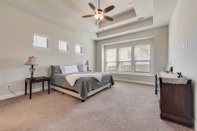 bedroom featuring a raised ceiling, ceiling fan, and light colored carpet