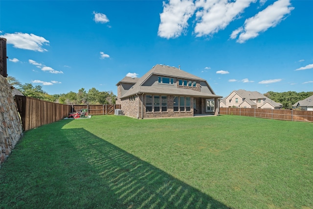 rear view of house with cooling unit and a lawn