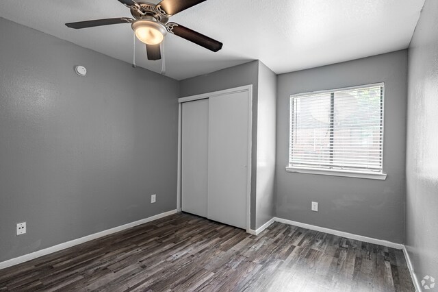 unfurnished bedroom featuring a closet, ceiling fan, and dark wood-type flooring