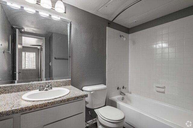 full bathroom with tiled shower / bath, vanity, toilet, and ceiling fan