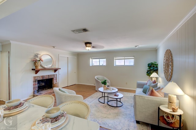 living room featuring light hardwood / wood-style floors, ornamental molding, and a fireplace