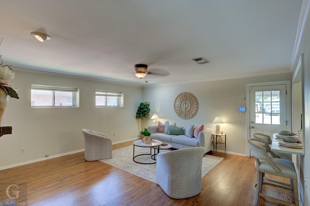 living room with light hardwood / wood-style floors, a wealth of natural light, crown molding, and ceiling fan