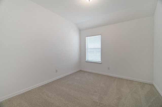 carpeted spare room featuring lofted ceiling