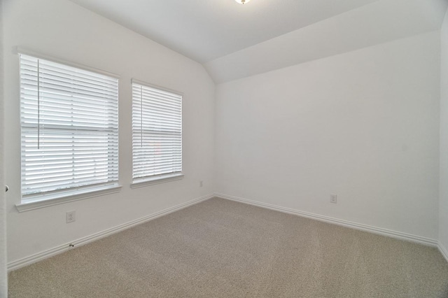 spare room with vaulted ceiling and carpet flooring