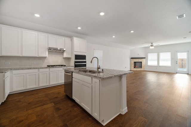 kitchen with sink, a center island with sink, appliances with stainless steel finishes, white cabinets, and backsplash