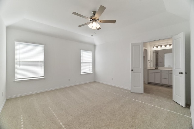 unfurnished bedroom featuring vaulted ceiling, light colored carpet, a raised ceiling, and ceiling fan