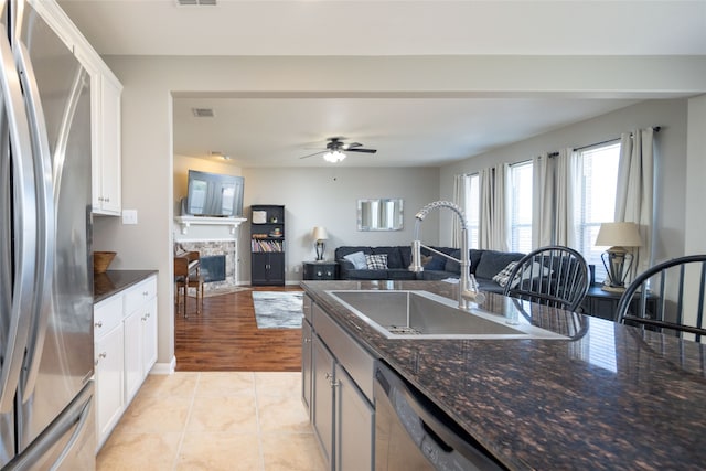 kitchen featuring light hardwood / wood-style floors, white cabinetry, stainless steel appliances, and dark stone counters