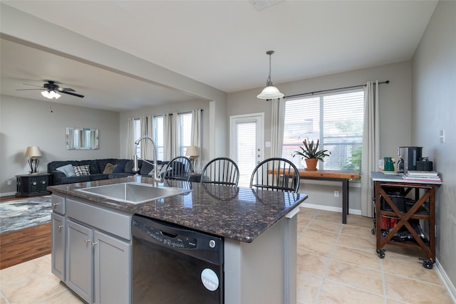 kitchen with dishwasher, sink, dark stone counters, pendant lighting, and a center island with sink