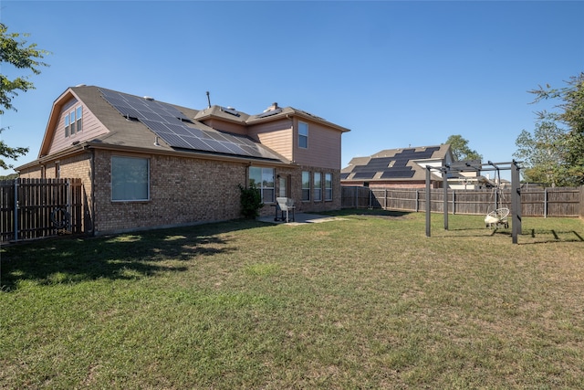 rear view of house featuring solar panels and a yard