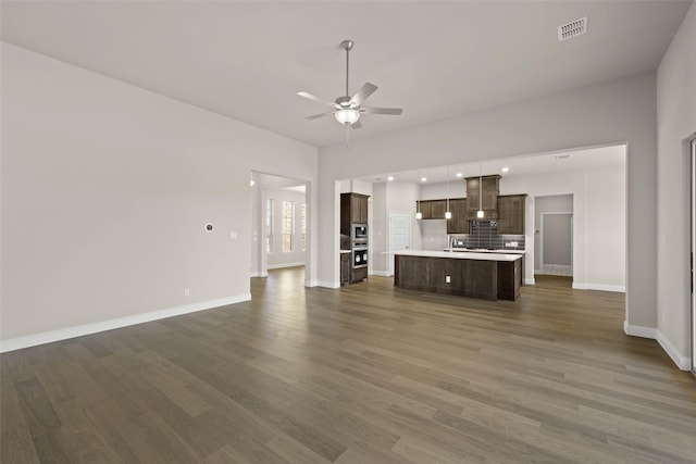 unfurnished living room featuring baseboards, ceiling fan, visible vents, and wood finished floors