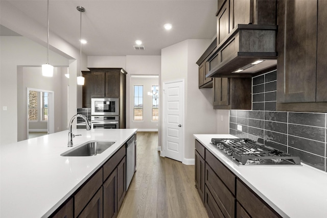 kitchen featuring light countertops, visible vents, appliances with stainless steel finishes, a sink, and dark brown cabinetry