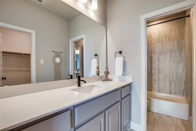 full bathroom with vanity, tiled shower / bath combo, and toilet