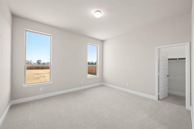 unfurnished bedroom with baseboards, multiple windows, and light colored carpet