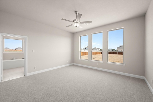 empty room with baseboards, a ceiling fan, and light colored carpet