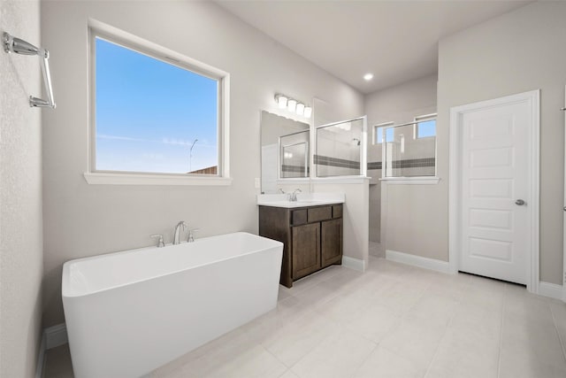 bathroom with baseboards, a soaking tub, tile patterned floors, walk in shower, and vanity