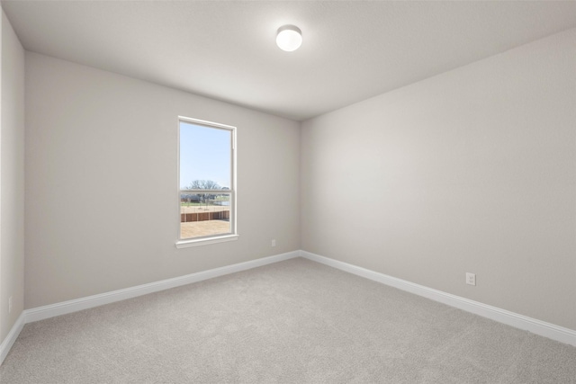 spare room featuring light colored carpet and baseboards