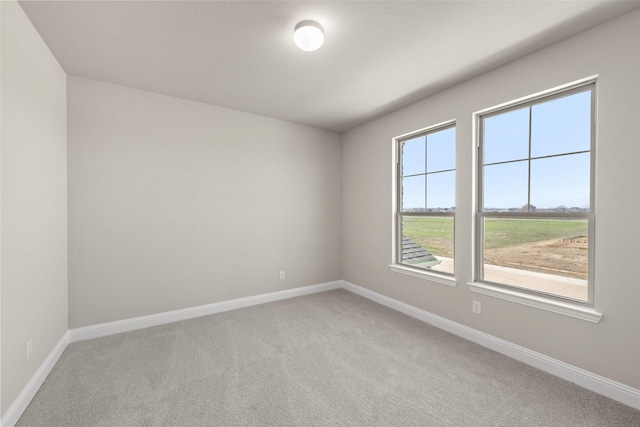 unfurnished room with baseboards and light colored carpet