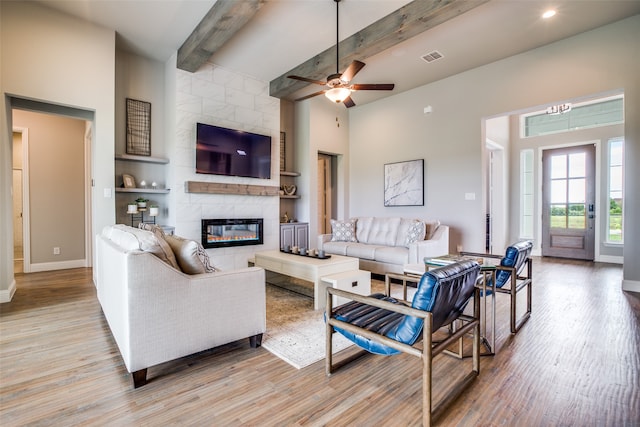 living room with ceiling fan, beam ceiling, light hardwood / wood-style flooring, and a tile fireplace