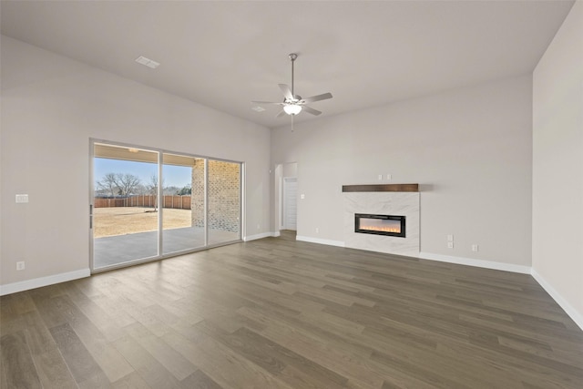 unfurnished living room with ceiling fan, a premium fireplace, wood finished floors, and baseboards