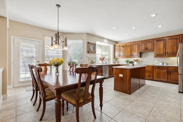 kitchen featuring a kitchen island, stainless steel appliances, tasteful backsplash, hanging light fixtures, and light tile patterned floors