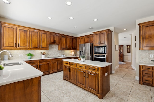 kitchen featuring decorative backsplash, black appliances, sink, and a center island