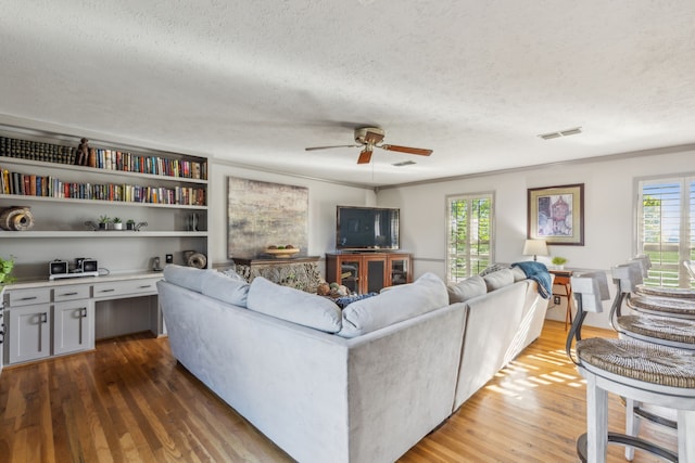 living room featuring ornamental molding, a textured ceiling, hardwood / wood-style flooring, and ceiling fan