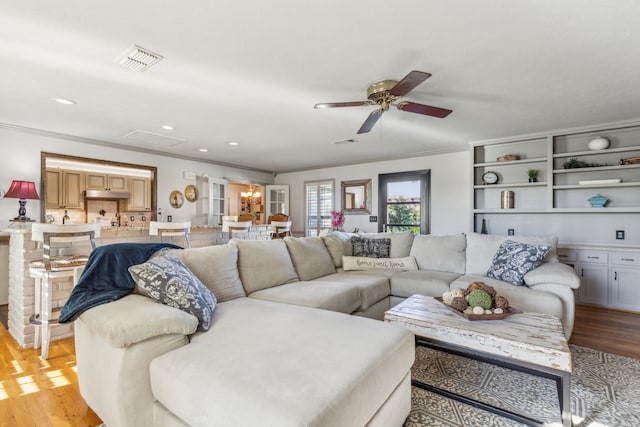 living room featuring light wood-type flooring, ornamental molding, and ceiling fan