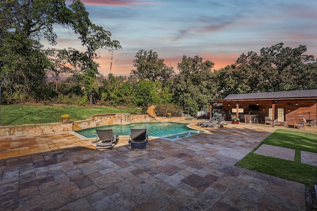 pool at dusk with a lawn and a patio