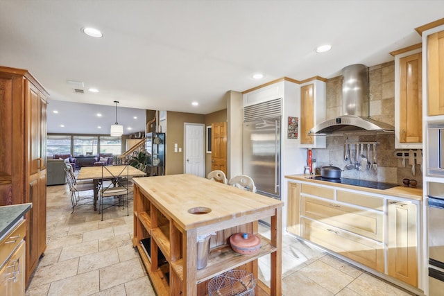 kitchen featuring stainless steel built in fridge, pendant lighting, wall chimney exhaust hood, backsplash, and black electric cooktop