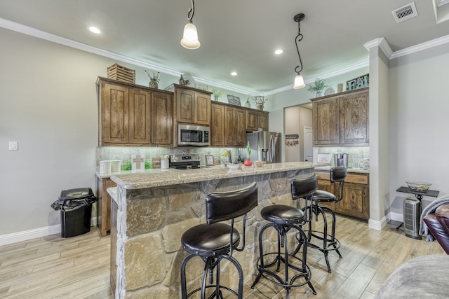 kitchen featuring appliances with stainless steel finishes, tasteful backsplash, a kitchen island with sink, and decorative light fixtures