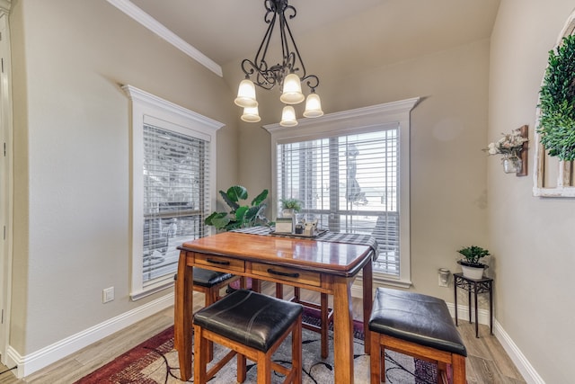 dining room with light hardwood / wood-style floors, ornamental molding, and a notable chandelier