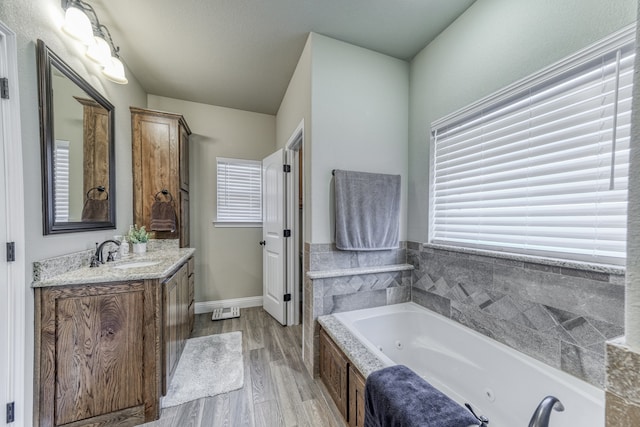 bathroom featuring vanity, a washtub, and hardwood / wood-style flooring