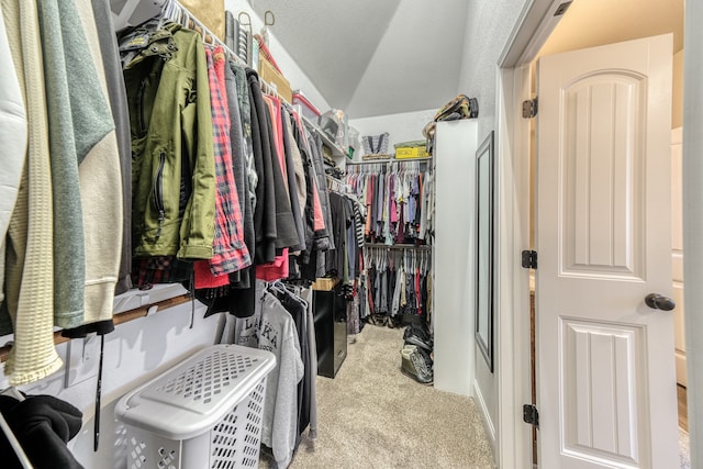 spacious closet with lofted ceiling and light colored carpet