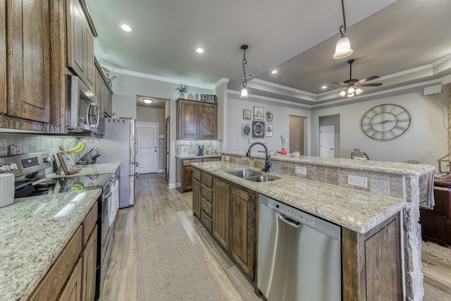 kitchen with sink, decorative light fixtures, a large island with sink, stainless steel appliances, and light wood-type flooring