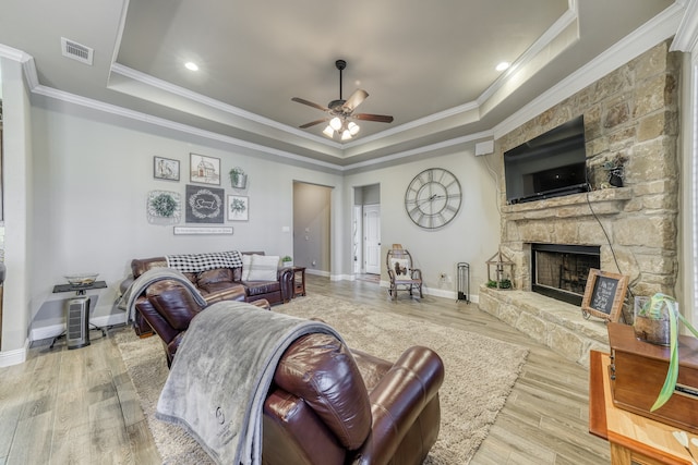 living room with light wood-type flooring, crown molding, and a tray ceiling